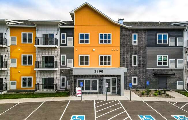 an apartment building with an orange and gray facade in a parking lot