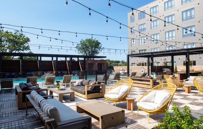 a rooftop lounge area with chairs and tables and a pool