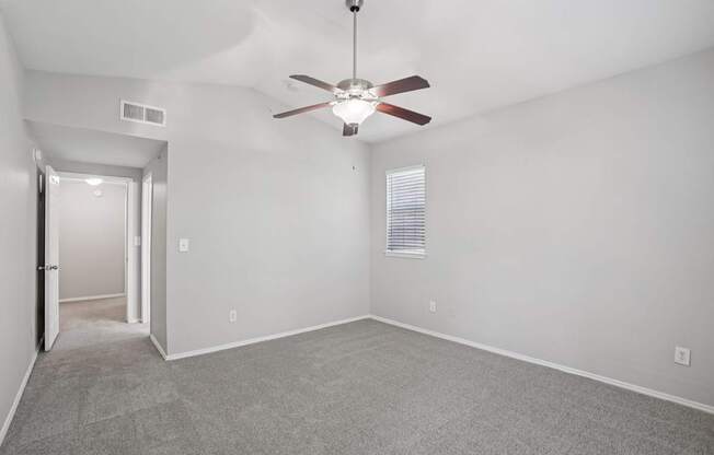 A room with a ceiling fan and carpeted floor.