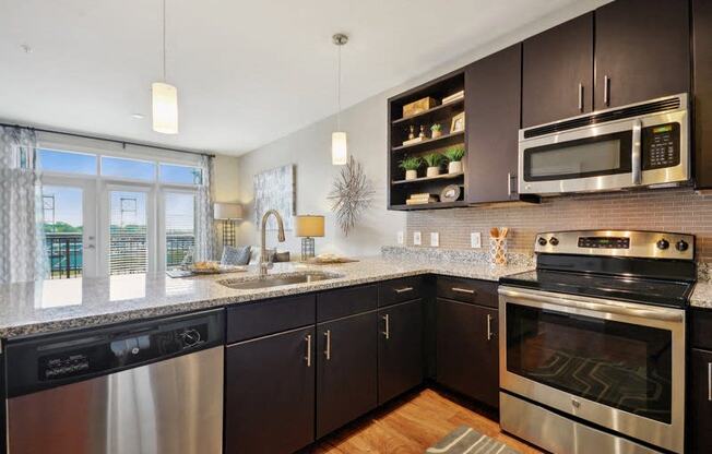 a modern kitchen with stainless steel appliances and granite counter tops at Link Apartments® Brookstown, Winston Salem, NC, 27101
