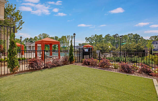 Outdoor area. Fenced in pool, big grass area outside of pool, and cabanas inside pool area at Ascent at Mallard Creek Charlotte, NC