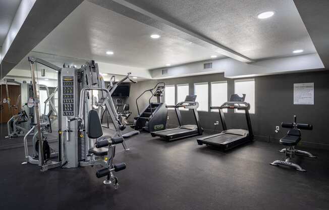 A gym with a variety of equipment including treadmills, weights, and a bench press at Verandas Apartments, West Covina, 91791