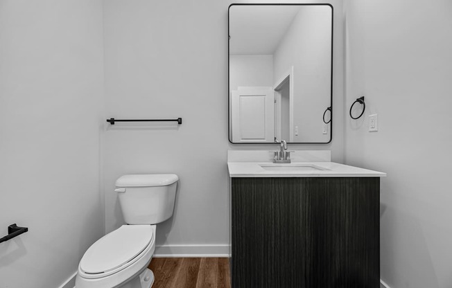 A bathroom with a toilet, sink, and mirror.