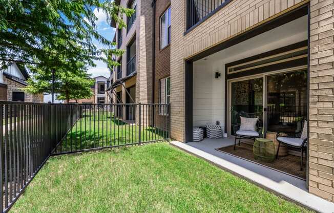 a patio with a fence and a lawn in front of a building