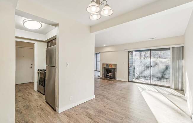 A modern kitchen with a refrigerator, oven, and a fireplace in the living room.