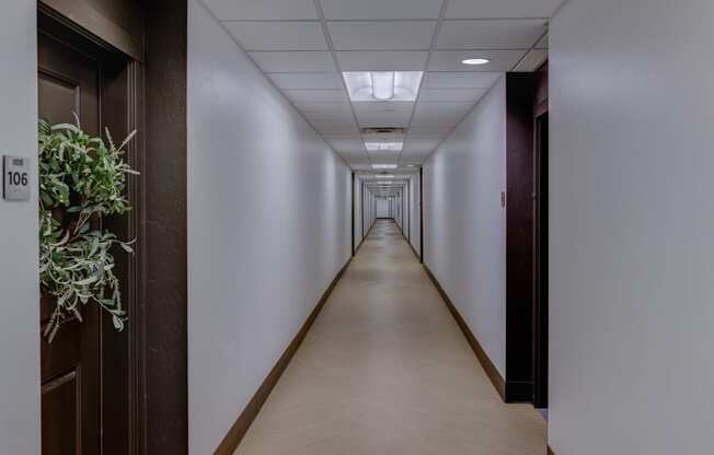 a long hallway with wood floors and white walls and wooden doors