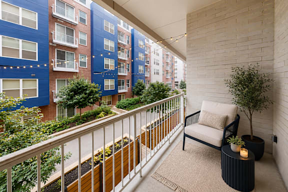 A balcony with a chair and a table with a plant on it.