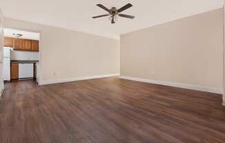 an empty living room with wood floors and a ceiling fan