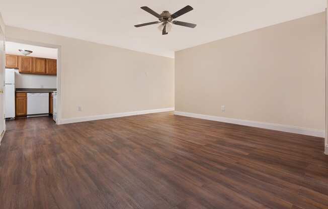 an empty living room with wood floors and a ceiling fan