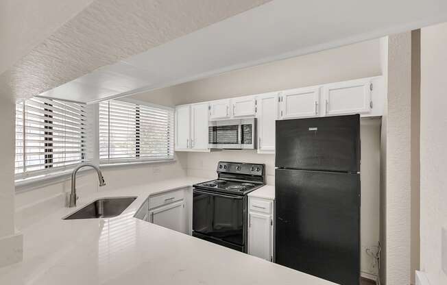 an empty kitchen with black appliances and white cabinets