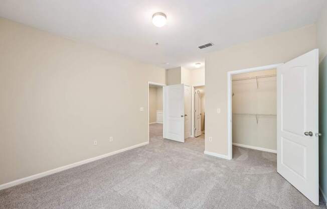 A bedroom with a carpeted floor , large closet and bathroom