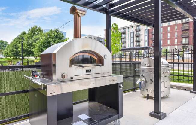 a pizza oven on a patio with a grill in the background