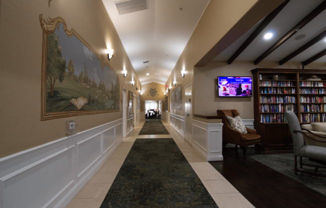 A long hallway with a painting on the wall and a TV on the wall.,A long hallway with a painting on the wall and a TV on the wall.