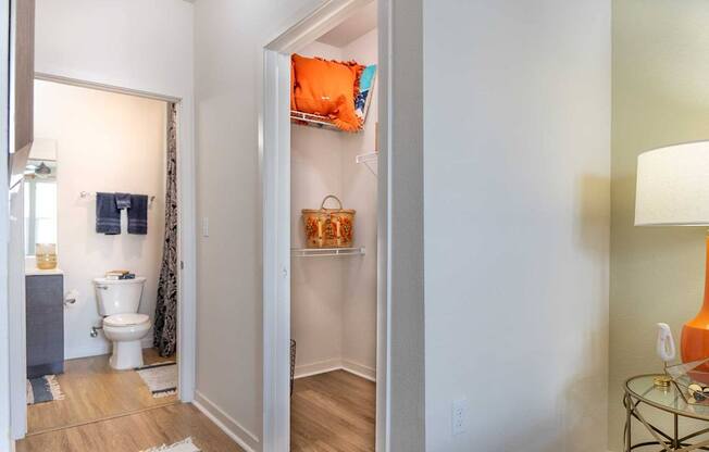 A bathroom with a toilet, a sink, and a small table with a lamp.