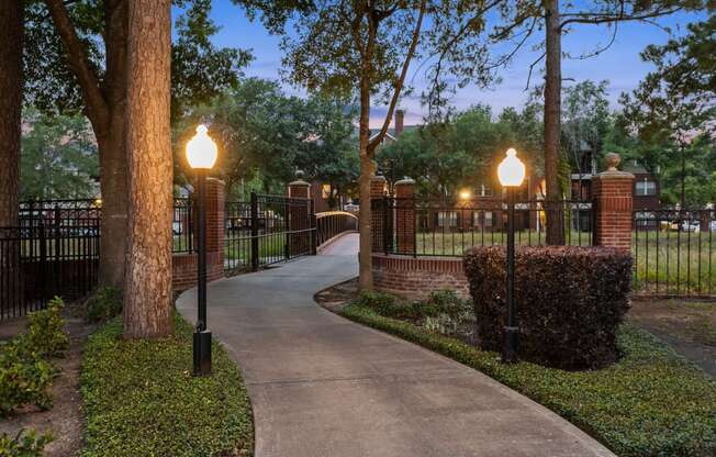 a walkway through a park with lamps and a fence at Villages of Cypress Creek, Texas, 77070