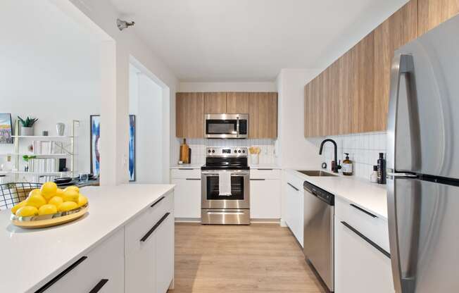 a kitchen with white cabinets and stainless steel appliances and a bowl of lemons on the counter