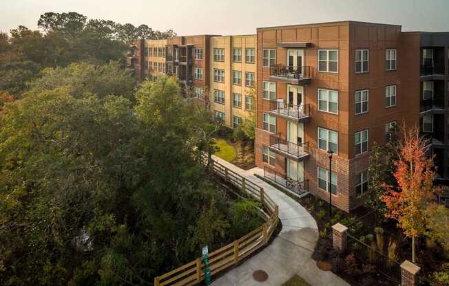 A view of apartment buildings with a walkway and trees in the foreground.