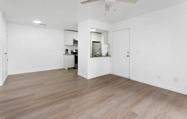A spacious room with a wood floor and a ceiling fan.