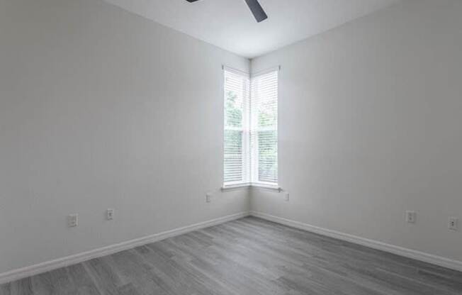 A room with a ceiling fan and a window with blinds.