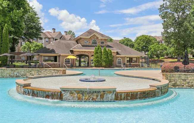 A resort style pool with many lounge chairs, umbrellas,  and tables