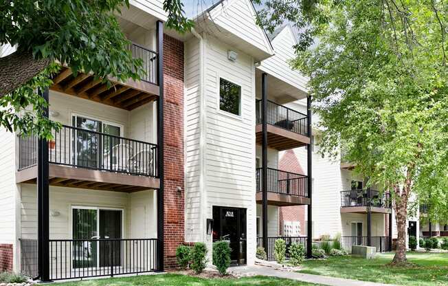 Apartment building with balconies and trees in front.