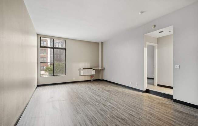 an empty living room with wood floors and a large window