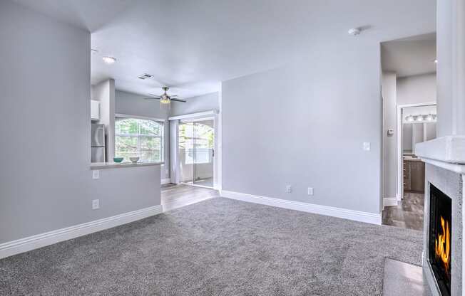 A living room with a grey carpet and a fireplace.