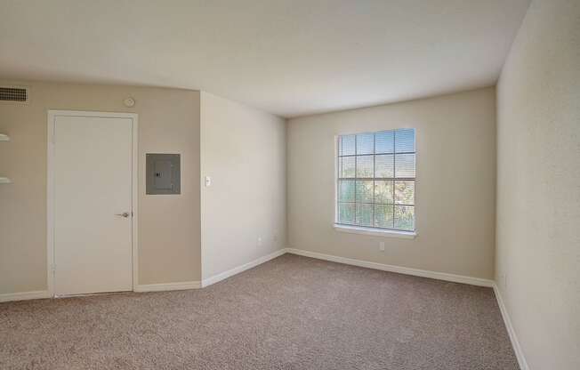 an empty living room with a door and a window