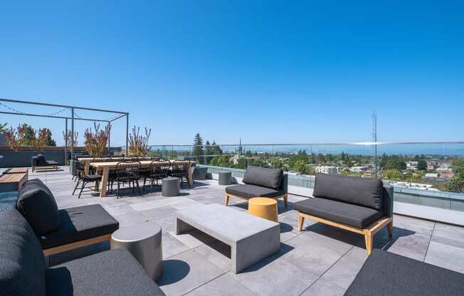 a roof top patio with chairs and tables overlooking the ocean