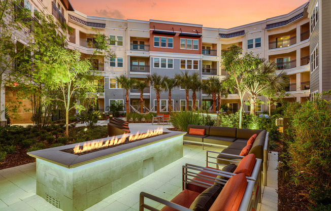 an outdoor lounge area with a fire pit in front of an apartment building