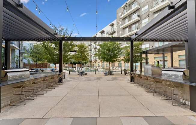 A patio area with chairs and tables under a roof.
