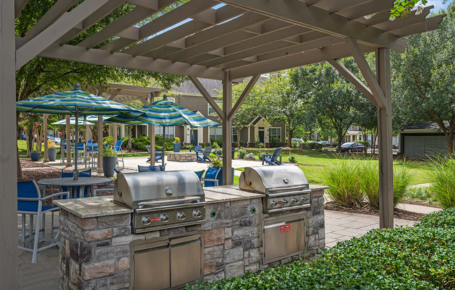 an outdoor kitchen with grills and umbrellas