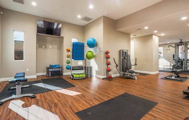 A spacious gym with a variety of equipment and a wooden floor.