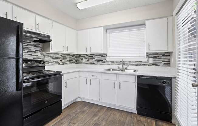 a kitchen with white cabinets and black appliances