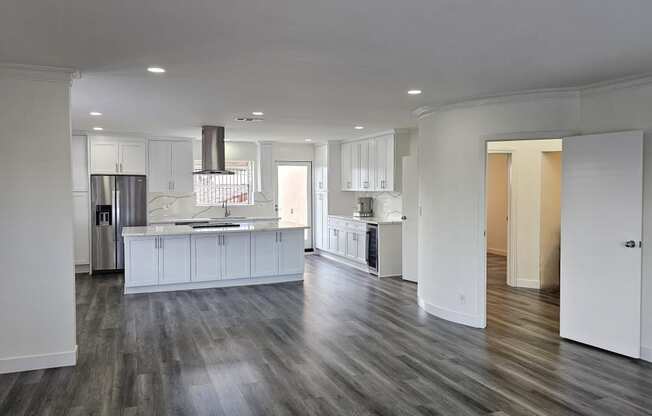 an open kitchen and living room with white cabinets and wood flooring