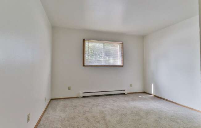 an empty living room with a window and white walls