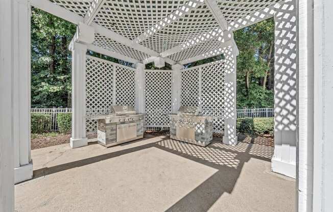 two bbq areas under a white gazebo with two grills