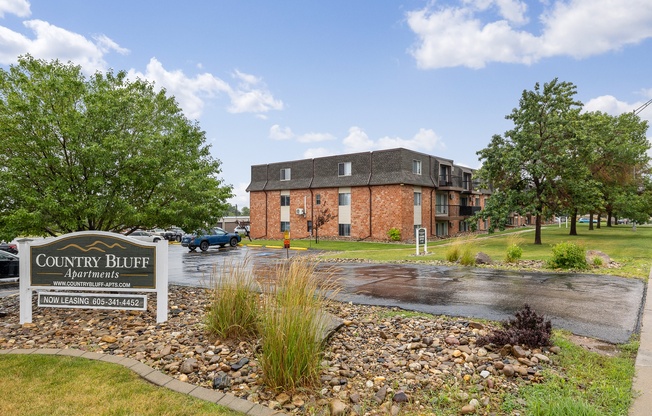 A sign for Country Bluff Apartments is in front of a brick building.