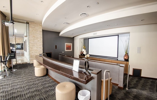 a reception area with a large screen tv on the wall and a long counter with stools