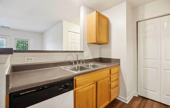 A kitchen with a black dishwasher and wooden cabinets.
