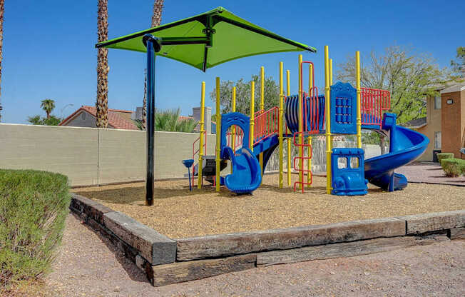 A playground with a blue slide and a green canopy.