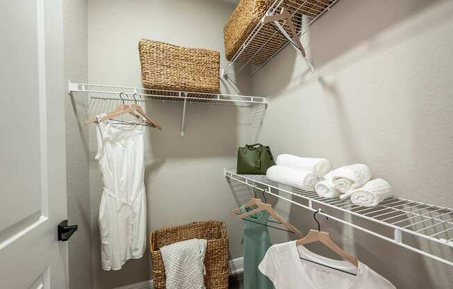 A white door is on the left of a hallway with clothes hanging on a rack.