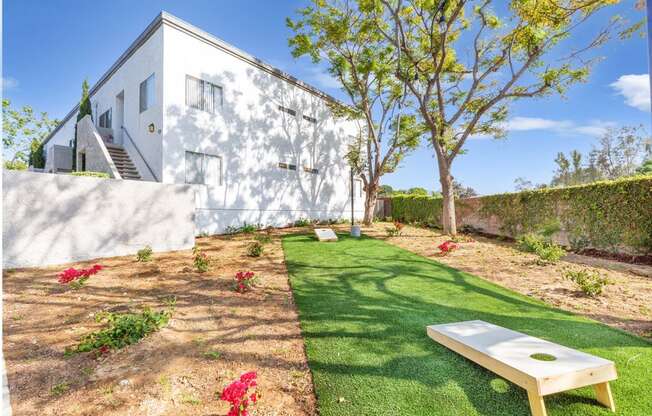 a backyard with a grassy area and a white house in the background