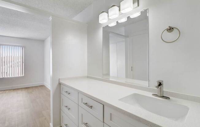 A bathroom with a sink, mirror, and lighting fixture.