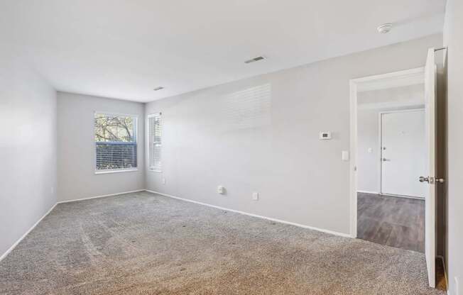 A spacious room with a carpeted floor and a door on the right side.