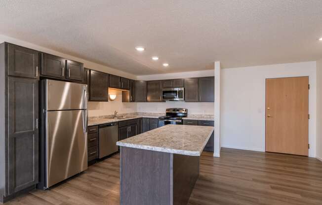 a kitchen with stainless steel appliances and a marble counter top. Fargo, ND Stonebridge Apartments