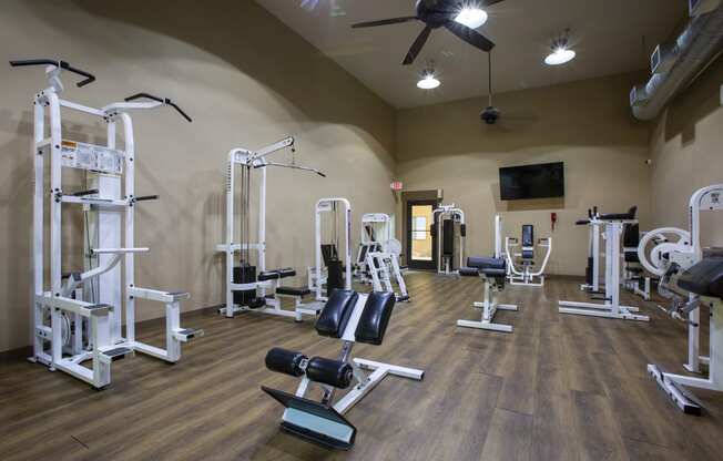 a gym with weights and exercise equipment on a wood floor