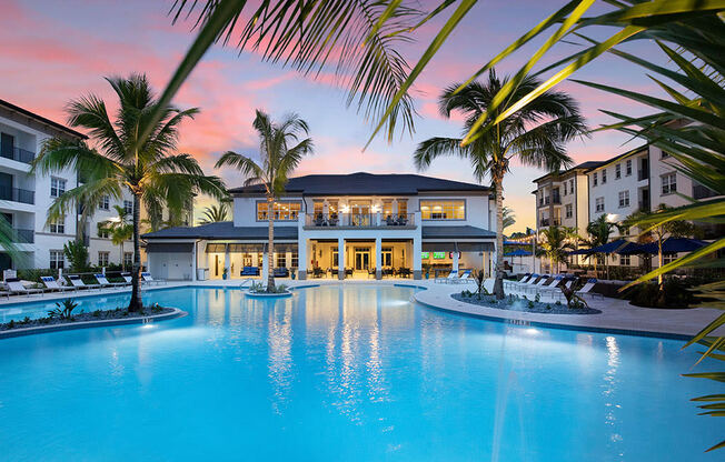 a large swimming pool in front of a resort with palm trees