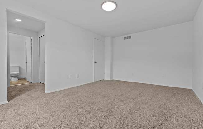 an empty living room with carpet and a door to a bathroom at Edge At Farmington Hills - Farmington Hills, MI, Michigan, 48334