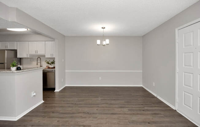A kitchen with white cabinets and a wooden floor.